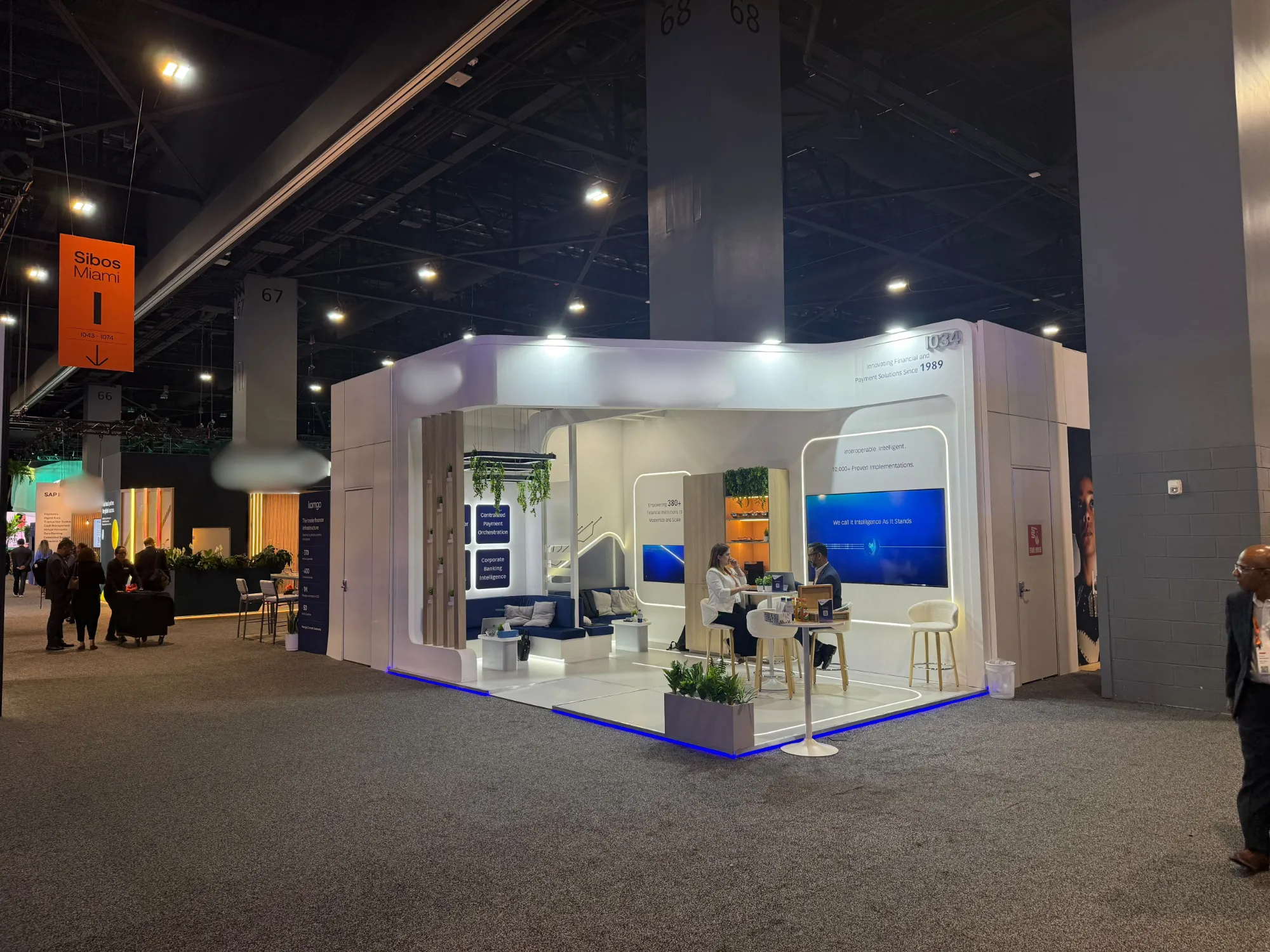 White curved-wall custom exhibition stand with blue LED base lighting at SIBOS 2026, Miami Beach Convention Center